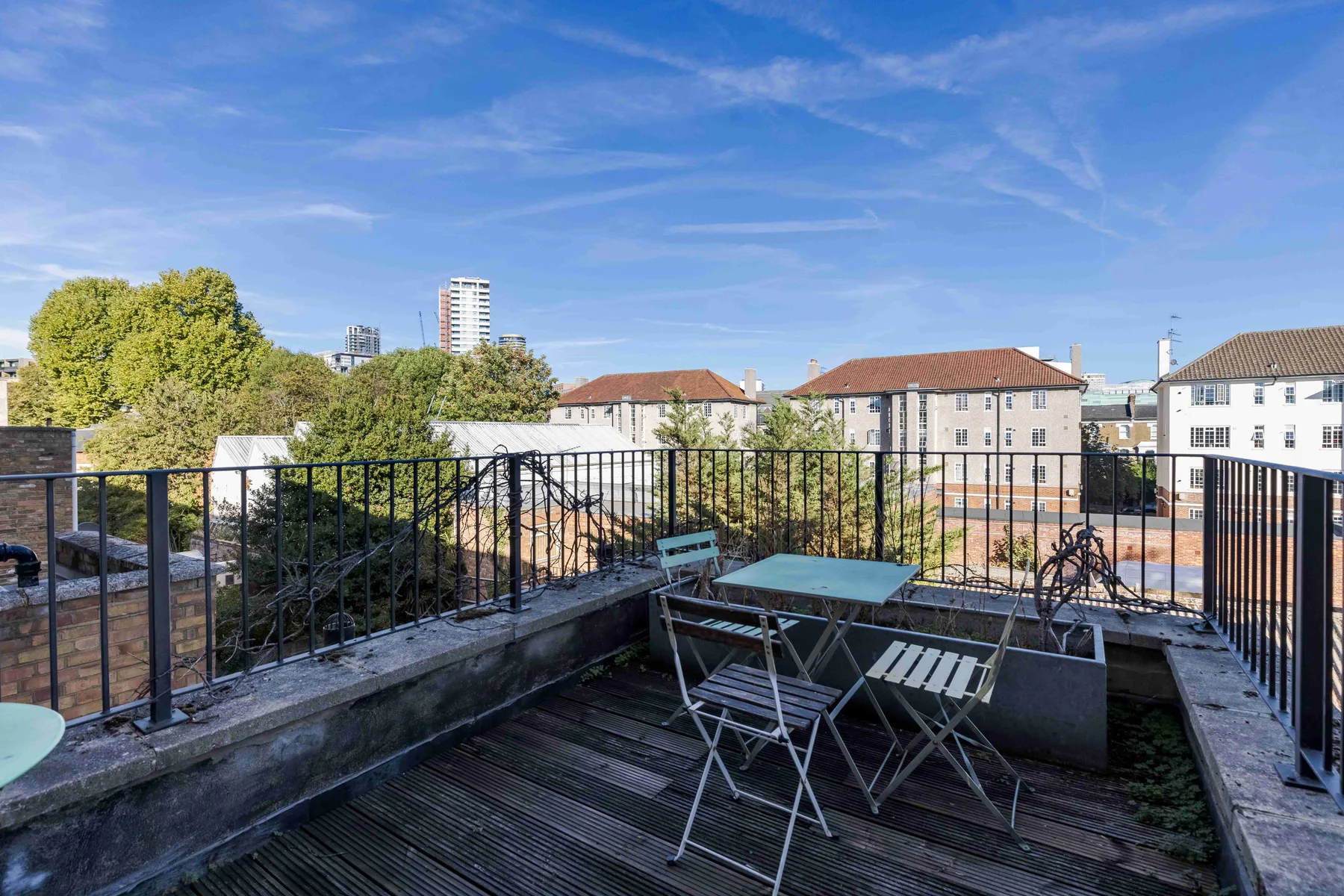 A rooftop terrace with outdoor seating and a view of nearby buildings.