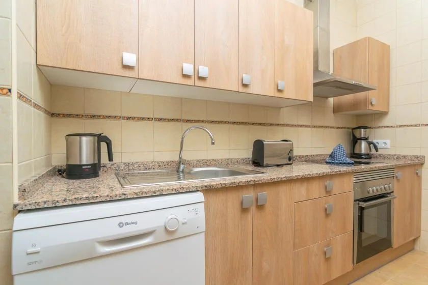 A kitchen with wood cabinets, a countertop, sink, and appliances.