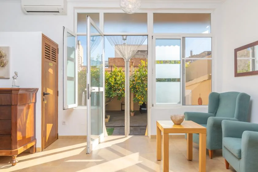 A bright sitting area opens onto a garden through wide glass doors.