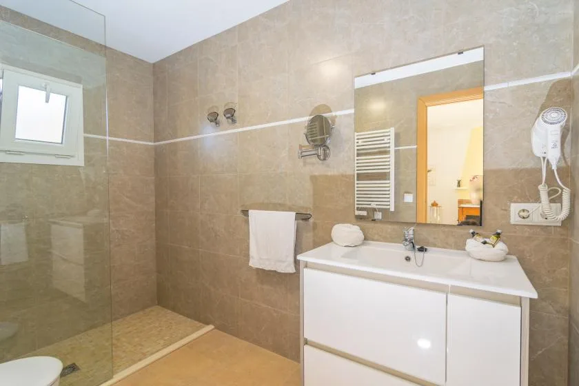 A tiled bathroom with a glass shower, sink, and large mirror.
