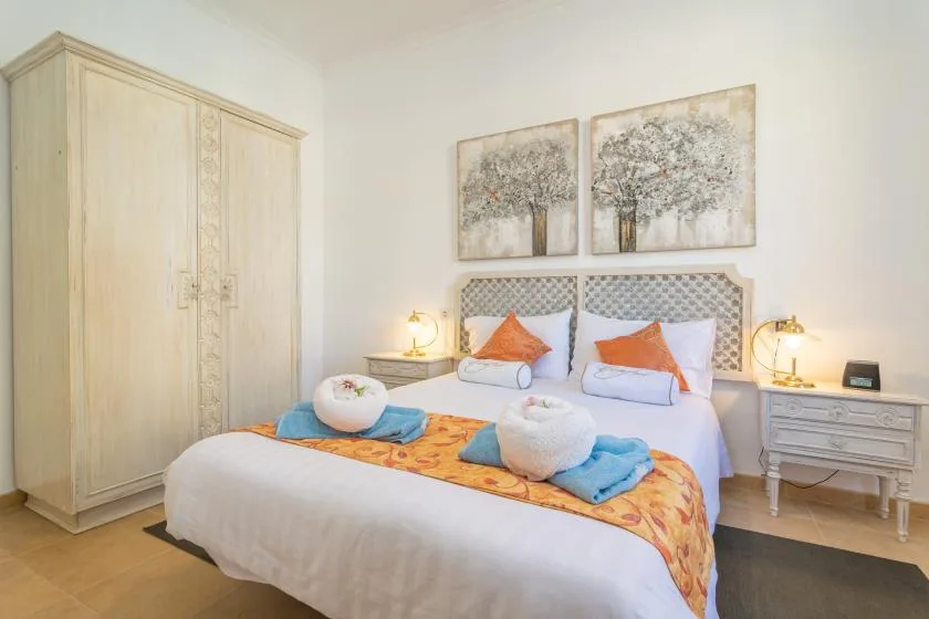 A bedroom with a double bed, colorful bedding, and a large wardrobe.