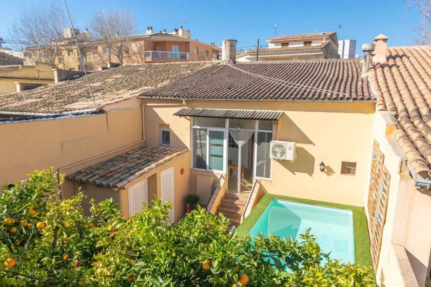 A sunny courtyard with a small swimming pool beside a tiled-roof building.