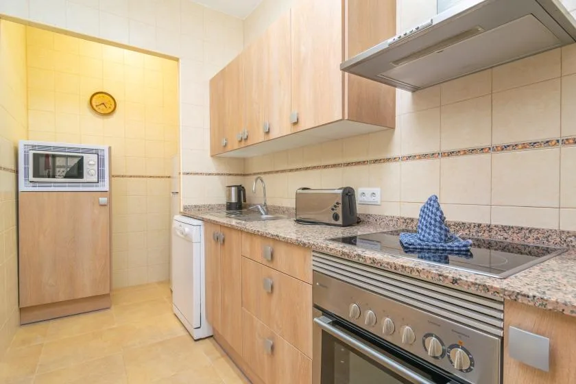 A bright kitchen with wood cabinets, a countertop, and built-in cooking appliances.