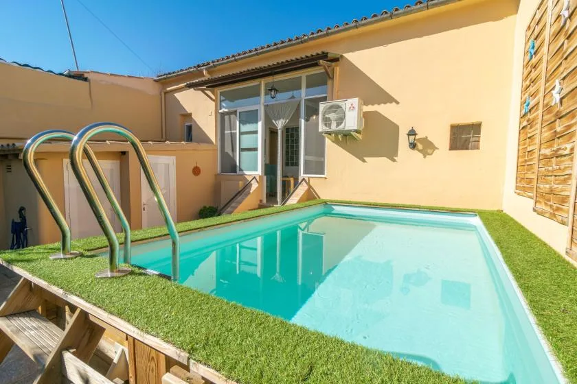An outdoor swimming pool beside a beige building, with a glass doorway and windows.
