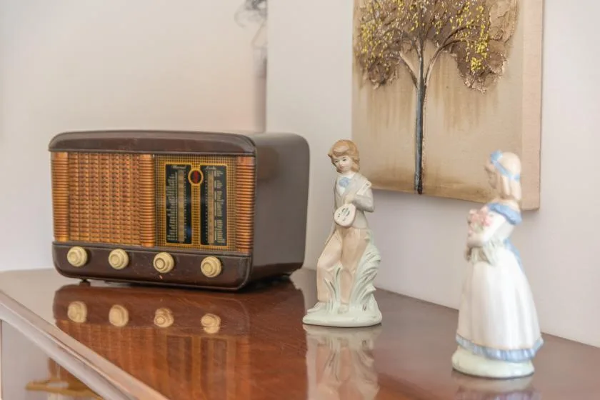 A vintage radio and decorative figurines sit on a polished wooden table.