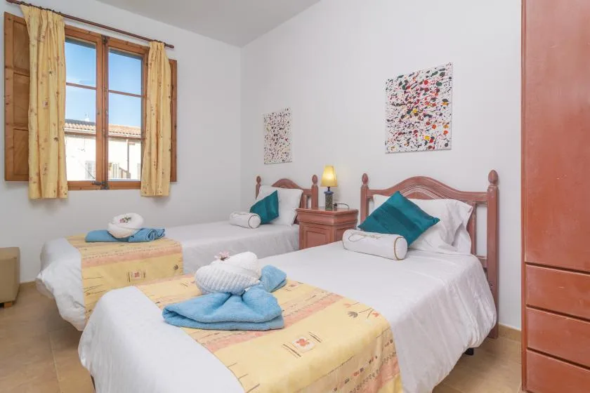 A bedroom with two beds, colorful bedding, and framed artwork on the walls.