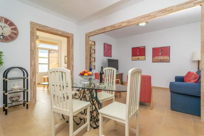 A dining area with a glass table and seating opens into a living room.