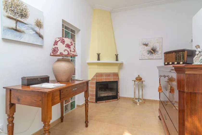 A living room with a fireplace, wooden furniture, and wall art.
