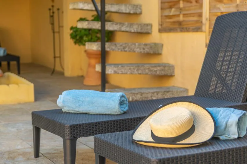 An outdoor seating area with dark woven loungers and a straw hat.