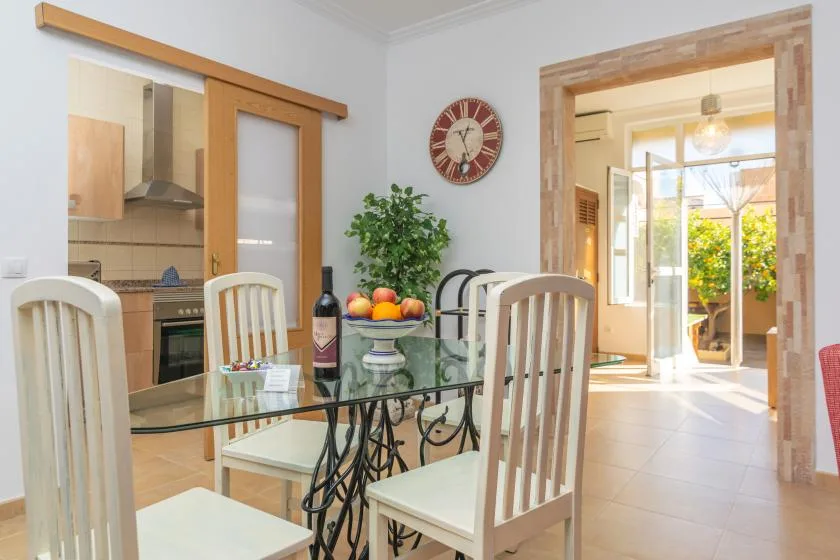 A dining area with a glass table and a bright adjoining room.