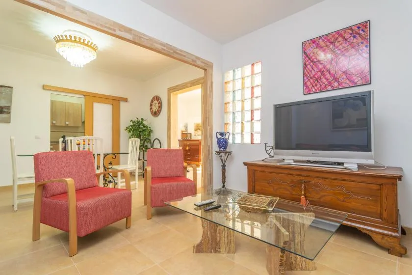 A living room with red seating, a television, and a glass coffee table.