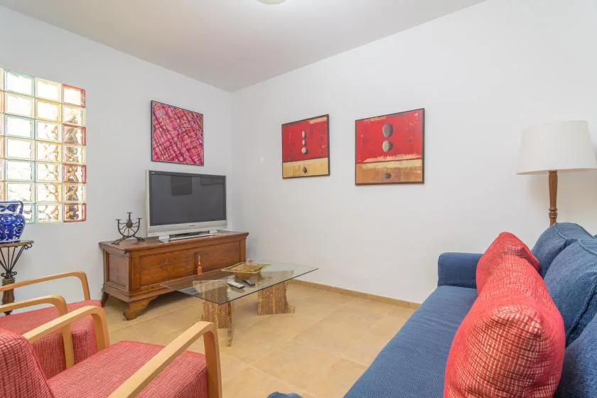 A living room with seating, a television, and colorful artwork on the walls.