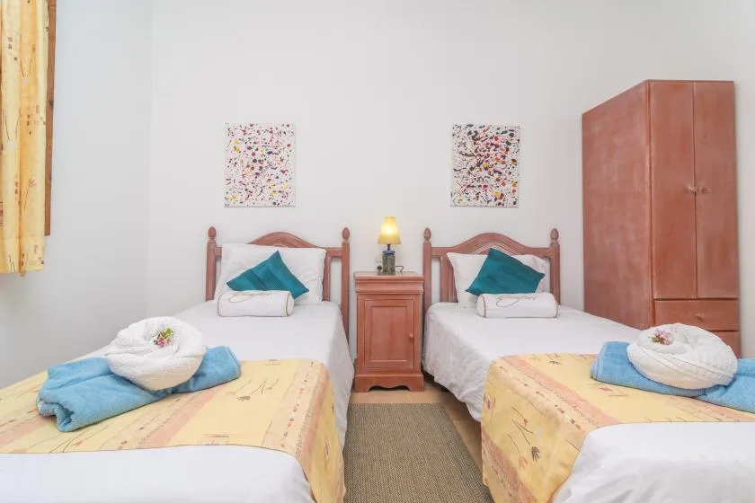 A twin bedroom with two beds, a nightstand, and a wardrobe.