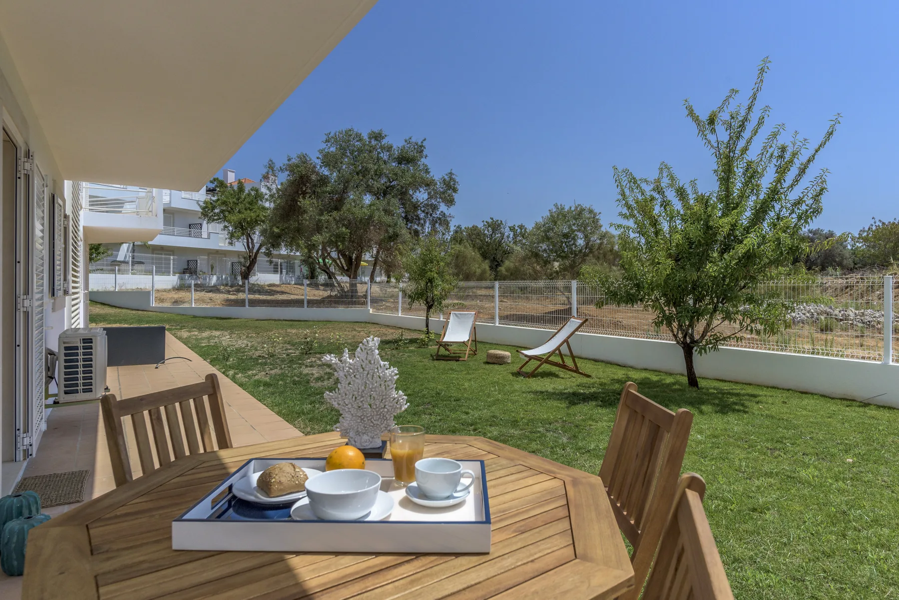 Un patio con asientos al aire libre y una mesa junto al césped.