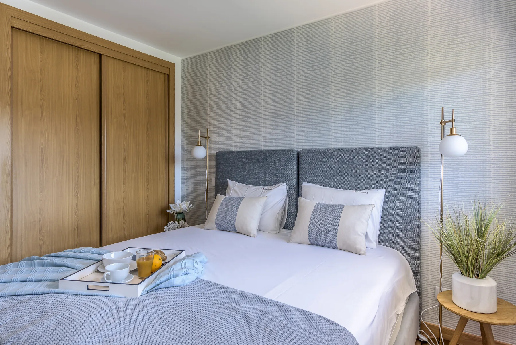 Un dormitorio con una cama bien tendida y armarios de madera clara.