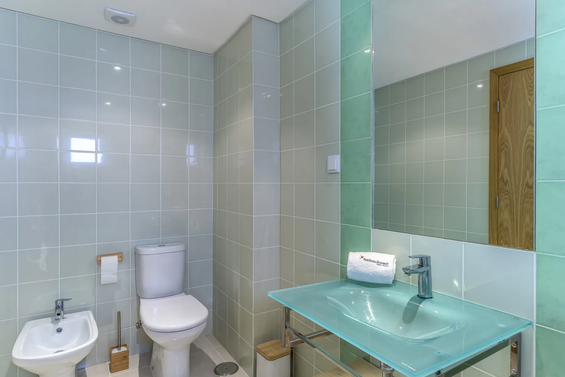 Un baño alicatado con inodoro, lavabo y espejo.
