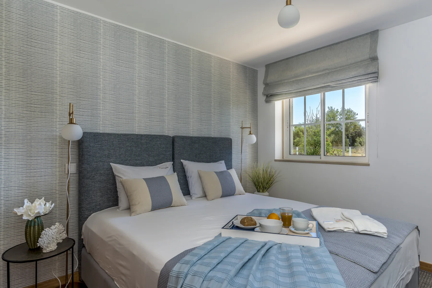 Un dormitorio con una cama bien hecha y una ventana con vistas a la vegetación.