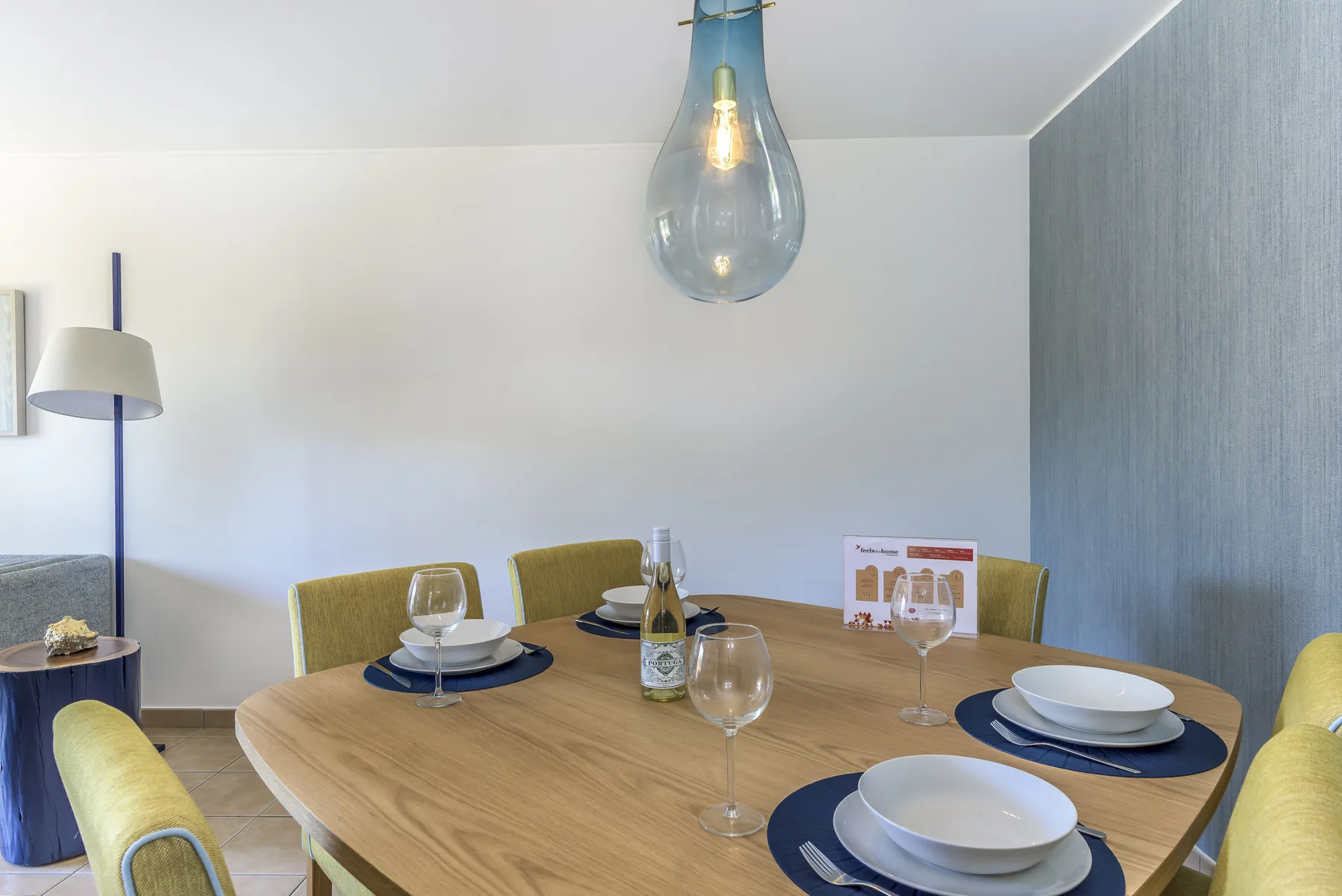 Comedor con una mesa de madera preparada con platos y cristalería.