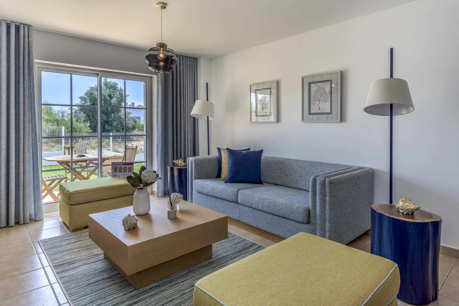Sala de estar con sofá gris, mesa de centro y una ventana grande.