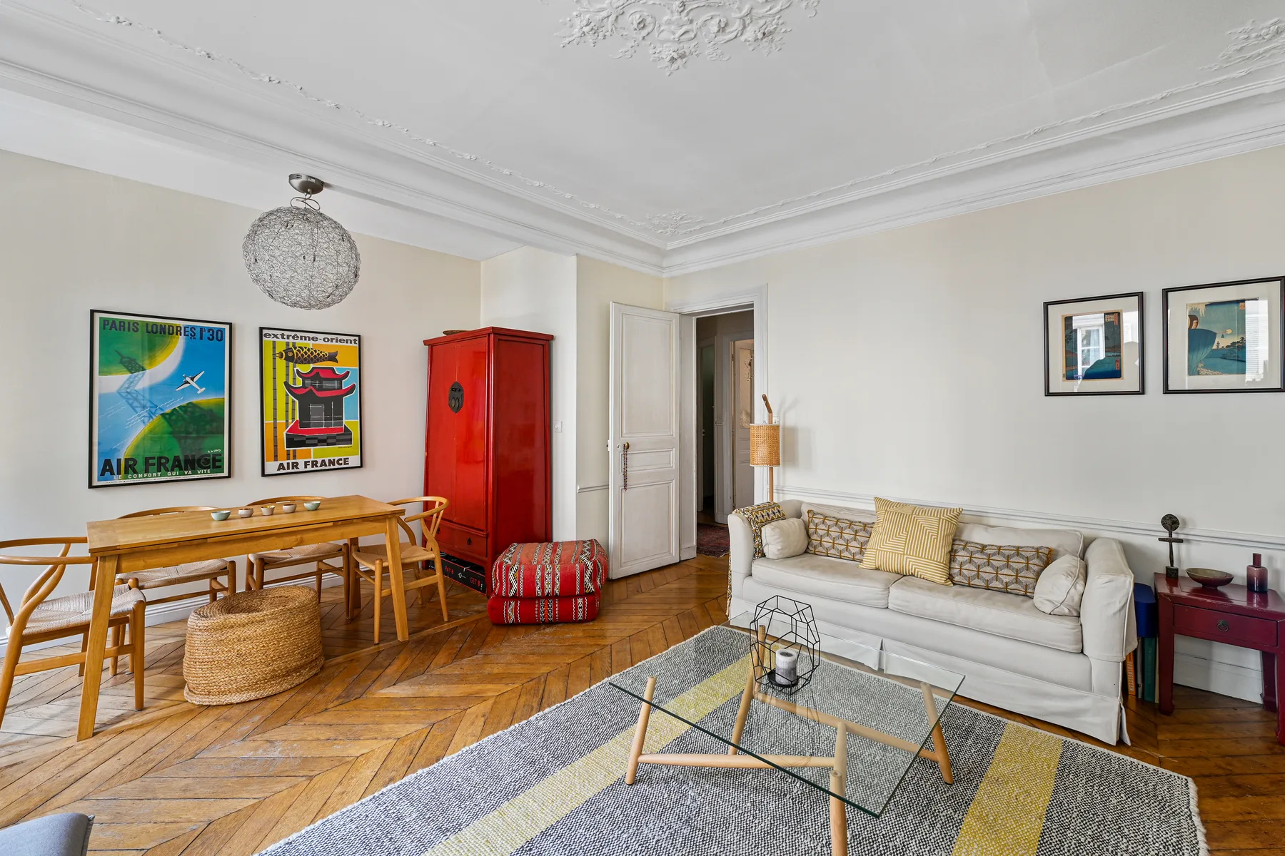 Una sala luminosa con sofá, mesa de centro de vidrio y mesa de comedor de madera.