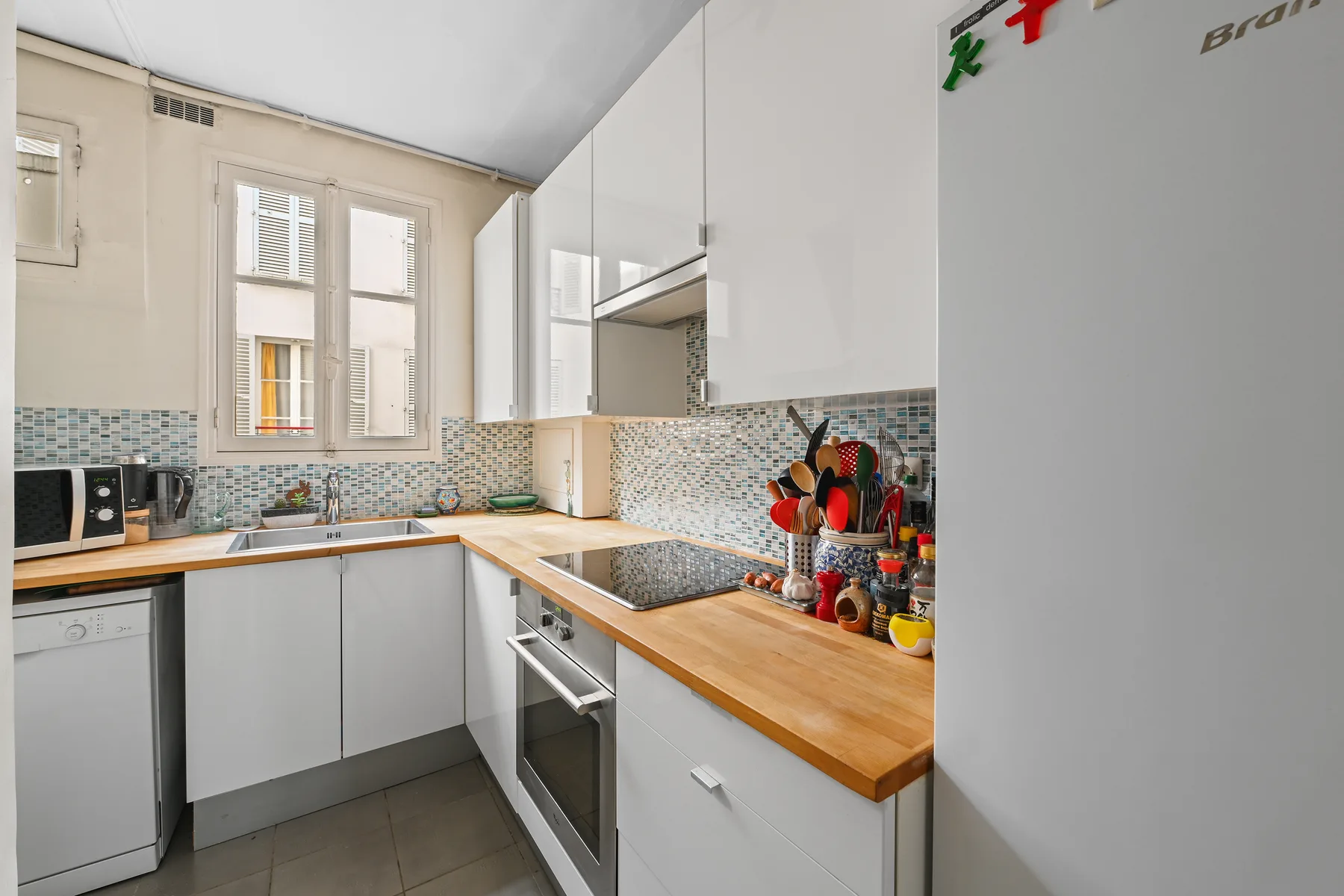 Una cocina luminosa con gabinetes claros, encimeras de madera y un salpicadero de azulejos.