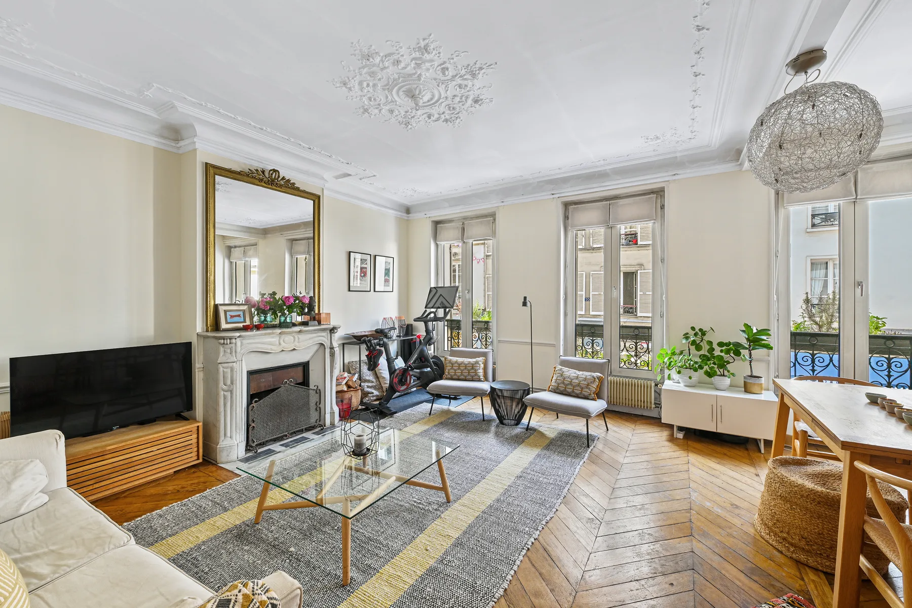 A bright living room with seating, a television, and tall windows.
