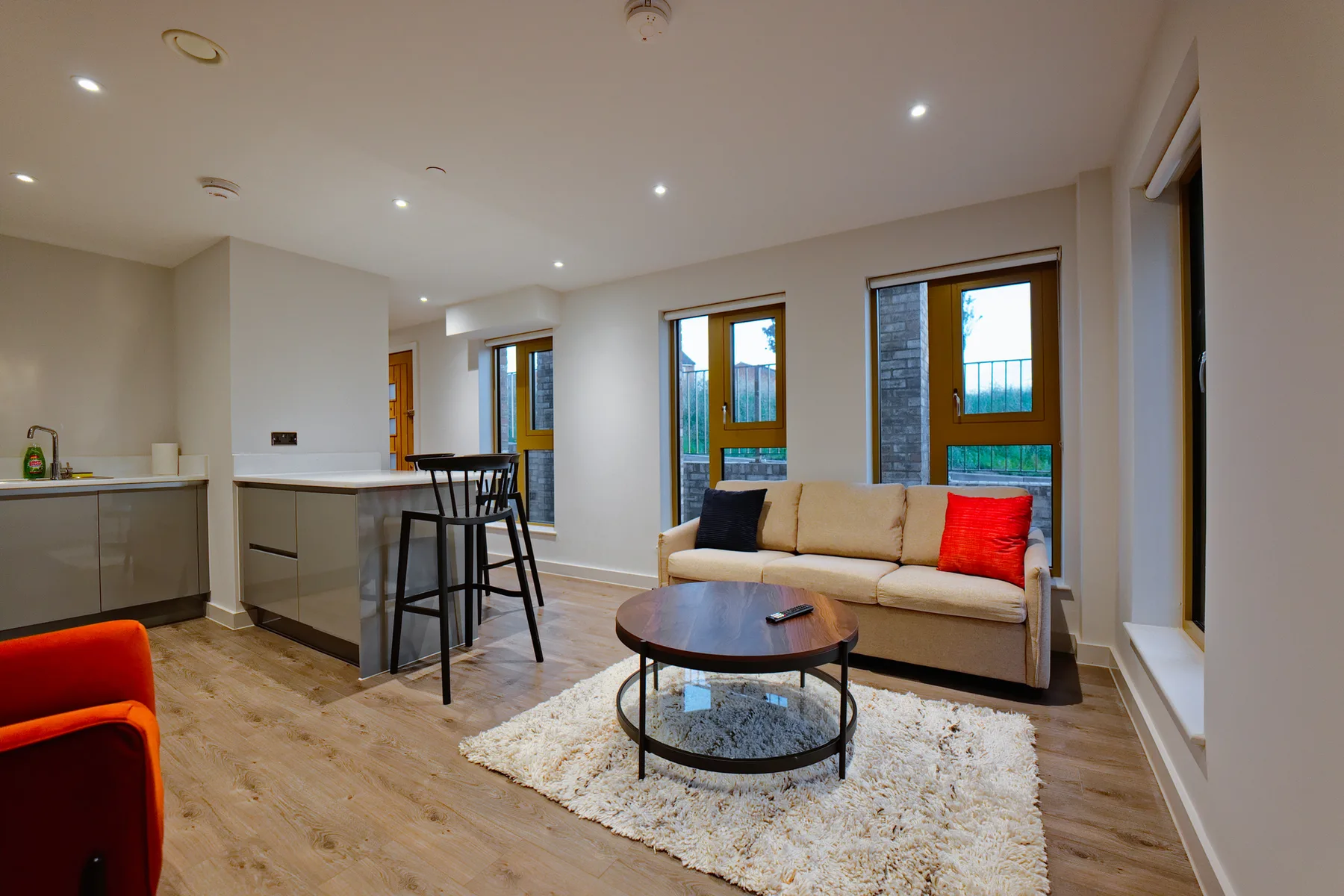A bright living room with a sofa, coffee table, and adjoining kitchen.
