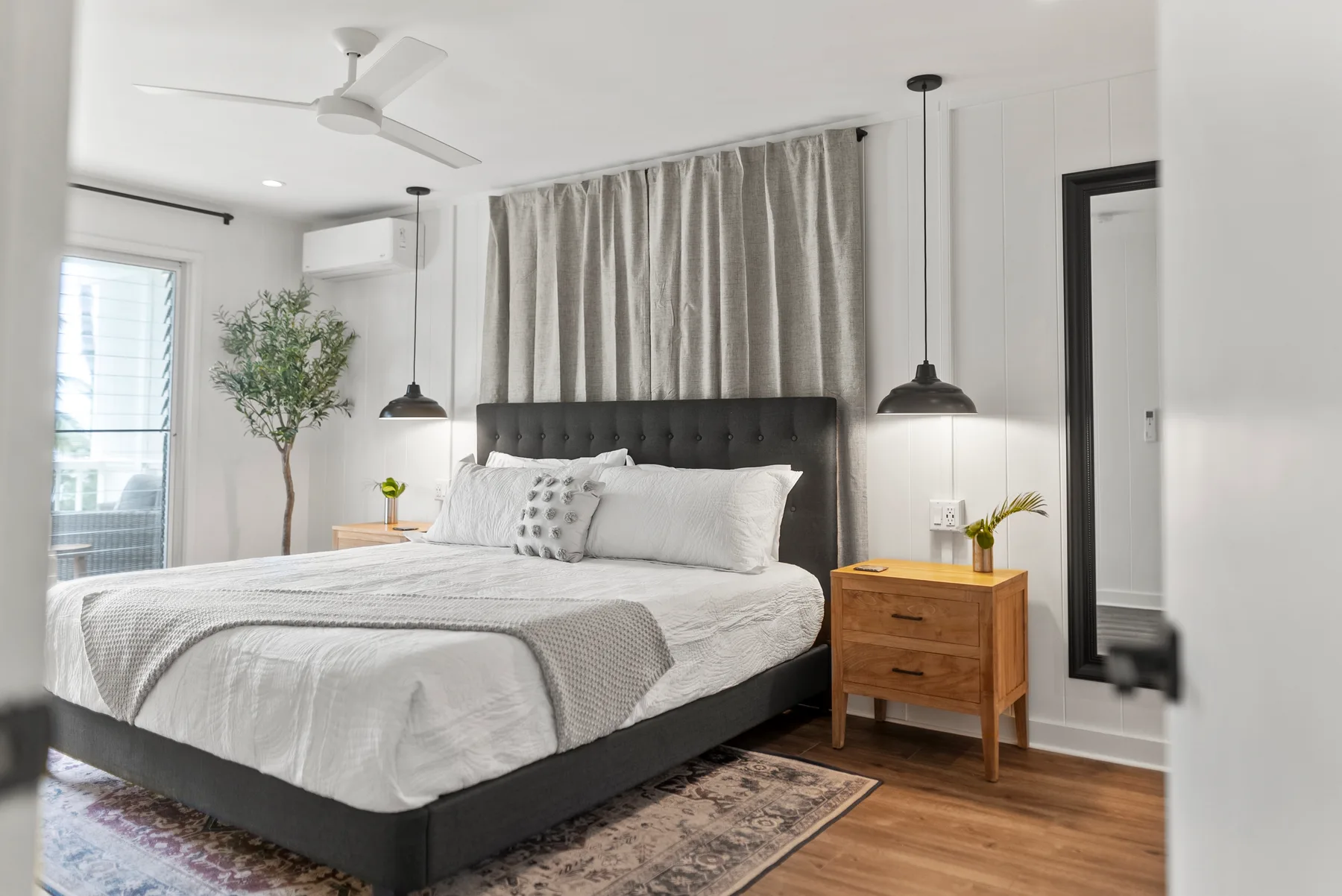Un dormitorio luminoso cuenta con una cama grande frente a una ventana con cortinas.