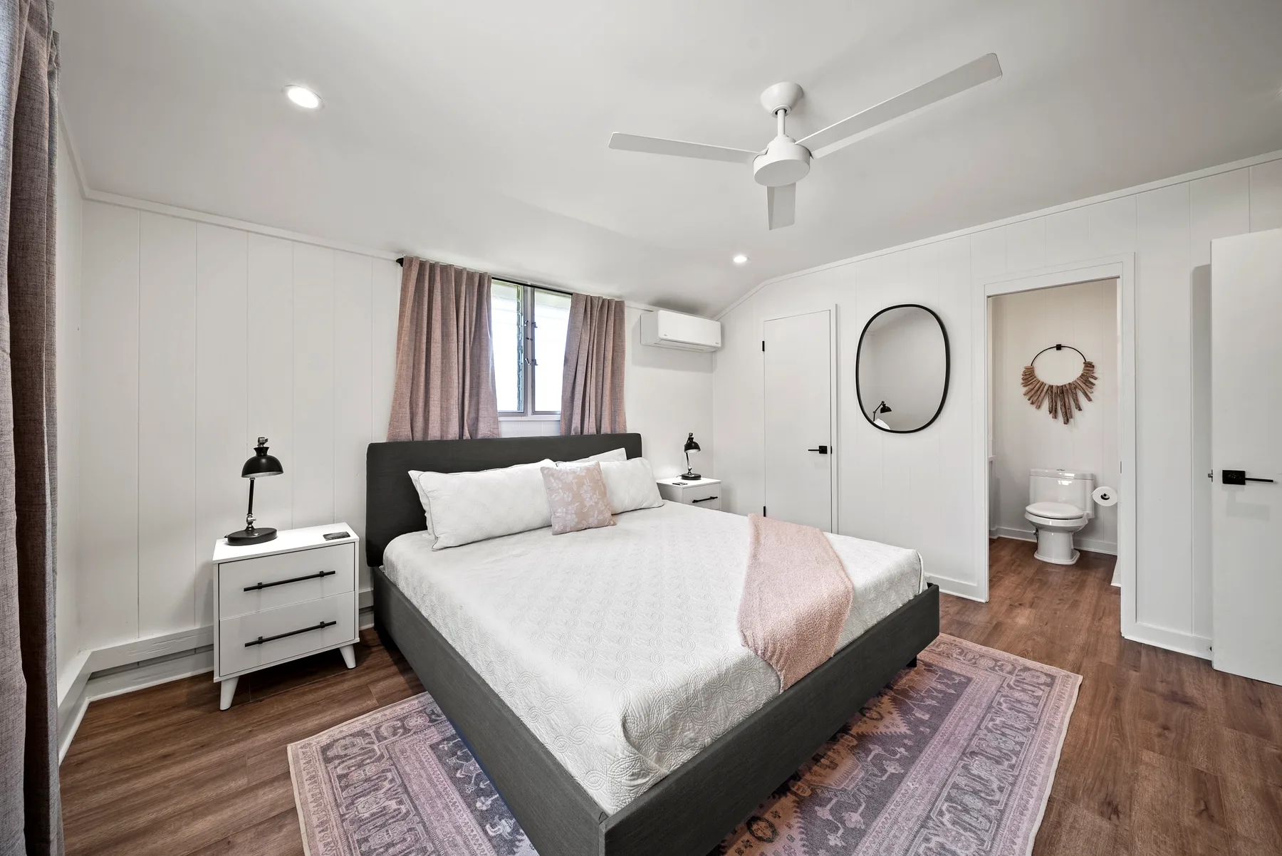 Un dormitorio con una cama, mesas de noche y un ventilador de techo.