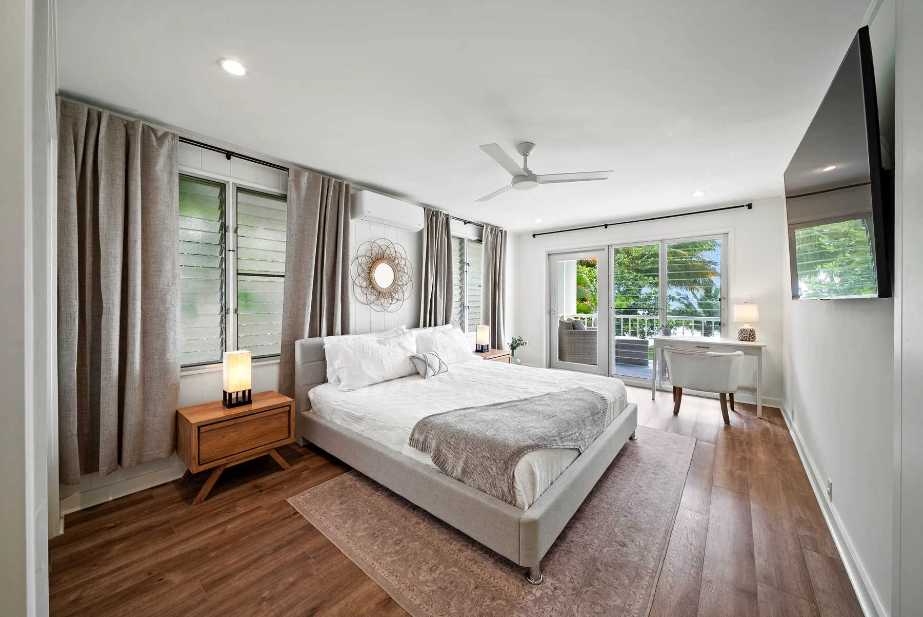 Un dormitorio luminoso con una cama, ventanas con cortinas y un escritorio.