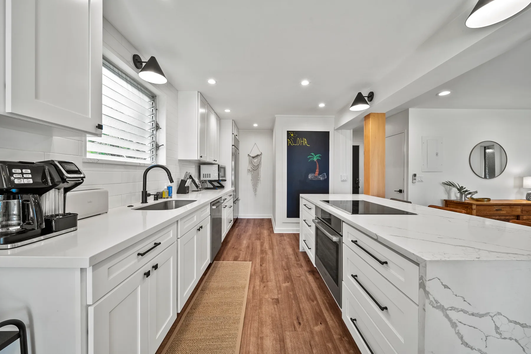 Una cocina luminosa con gabinetes blancos, encimeras y una isla central.