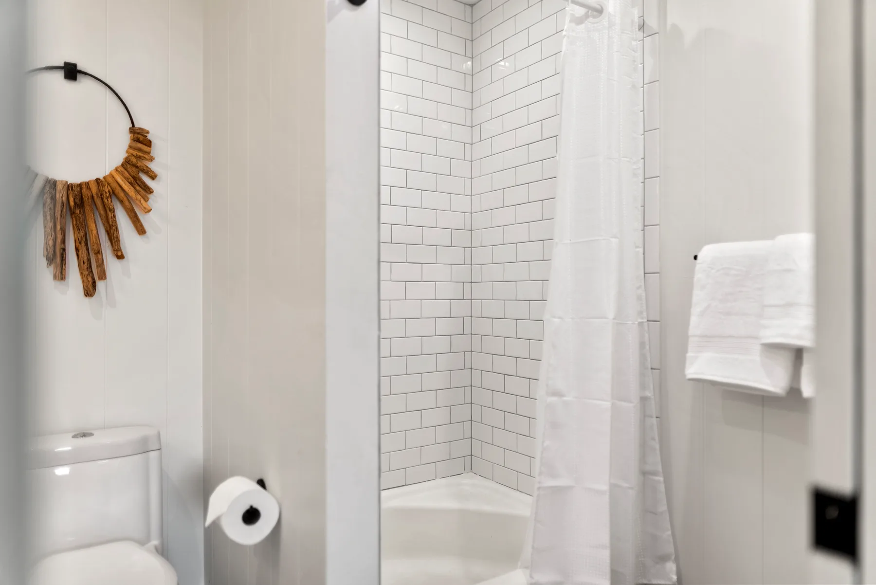 Un baño con una ducha alicatada y toallas colgadas en la pared.