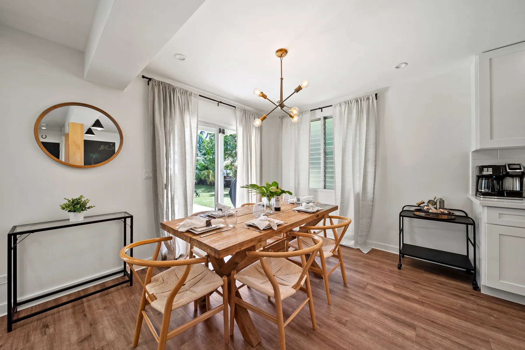 Un comedor luminoso con una mesa de madera y sillas junto a grandes ventanas.