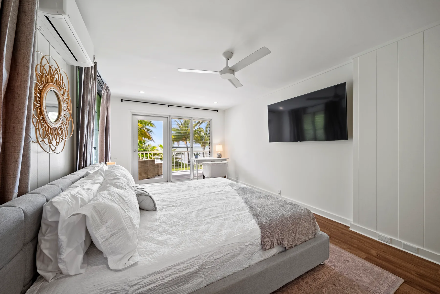 Un dormitorio luminoso con una cama grande y un televisor en la pared.