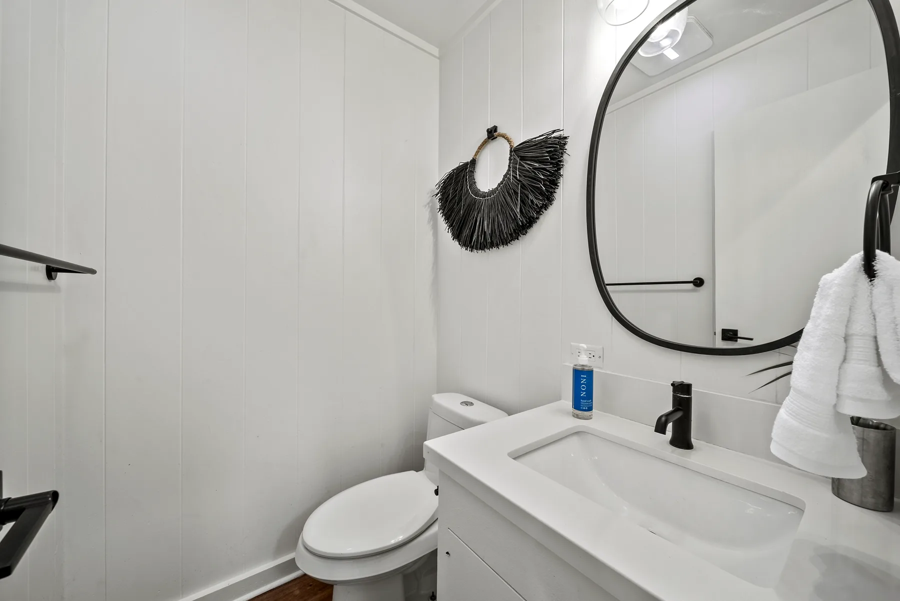 Un baño luminoso con lavabo, inodoro y un gran espejo de pared.