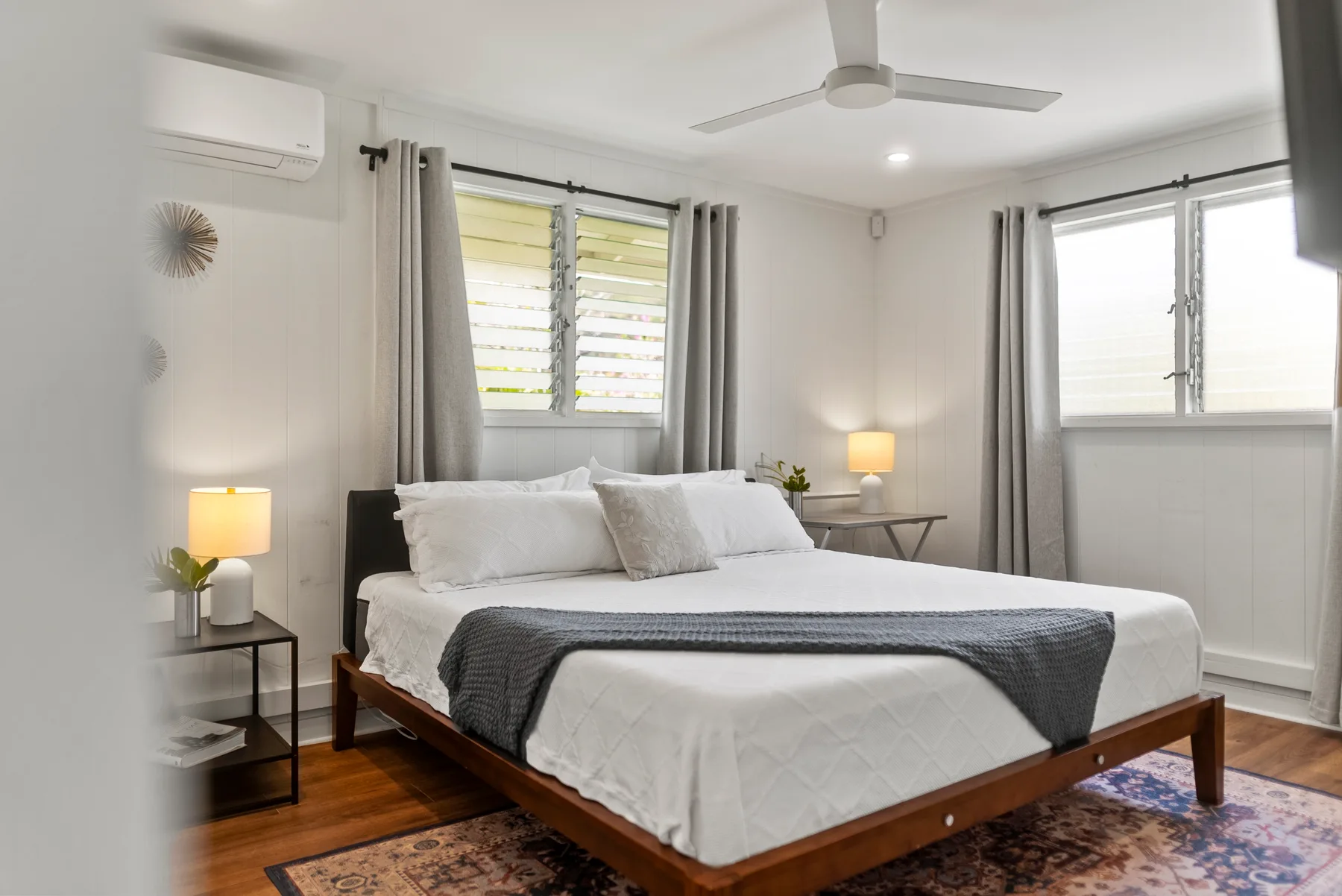 Un dormitorio luminoso con una cama bien arreglada y cortinas grises.