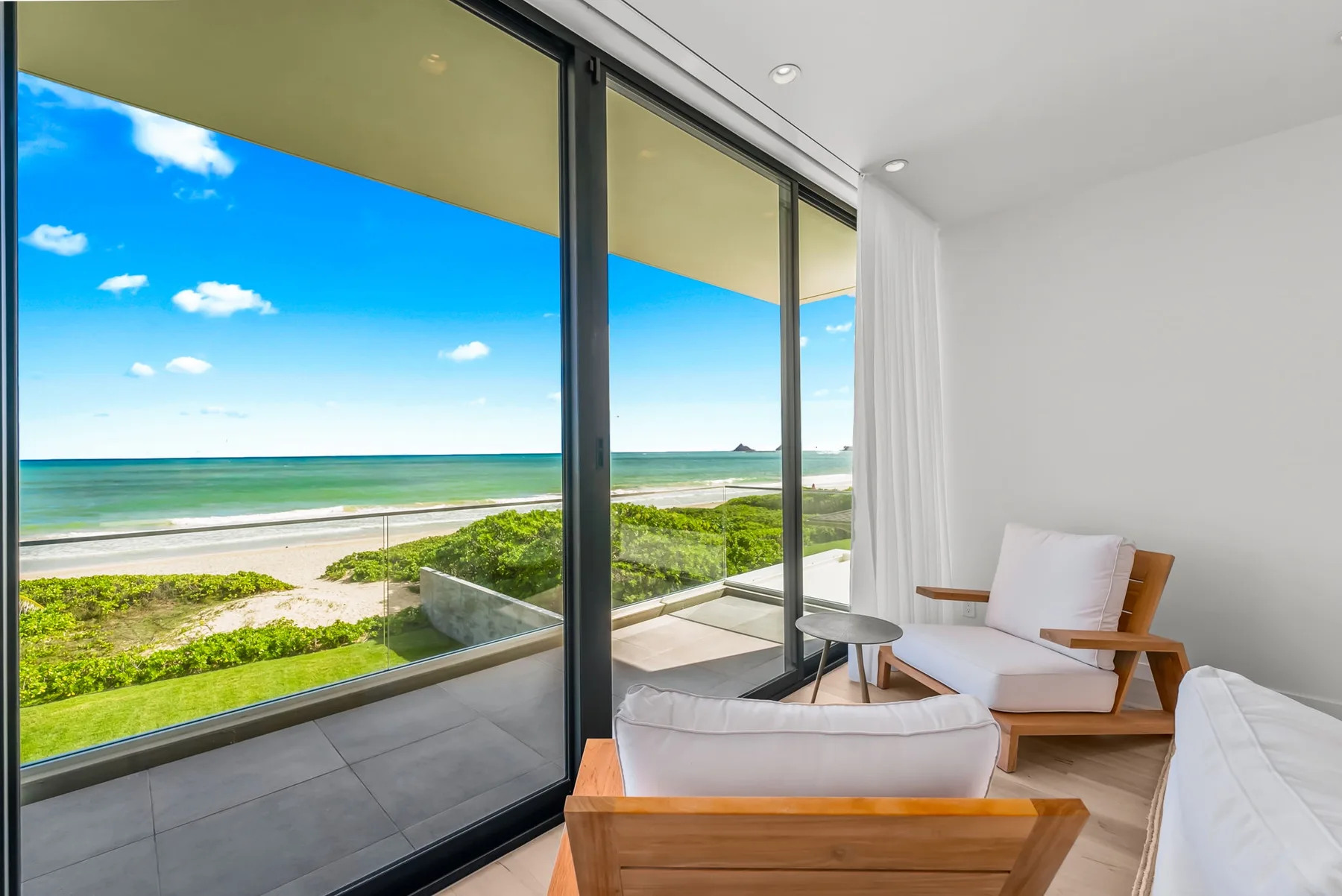 A bright living area opens onto a balcony overlooking the beach and ocean.