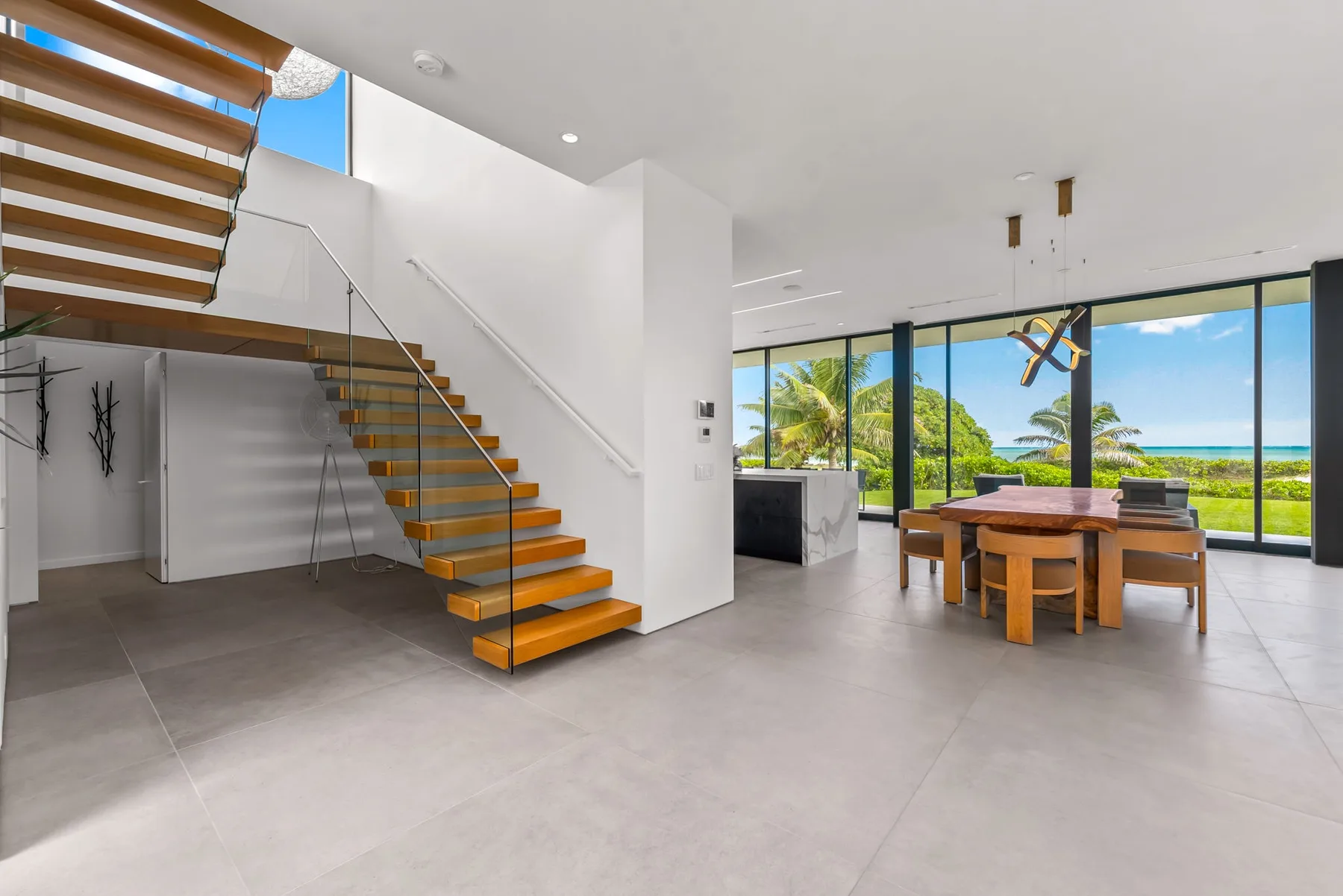 A bright open-plan dining area with a wooden table beside large windows.