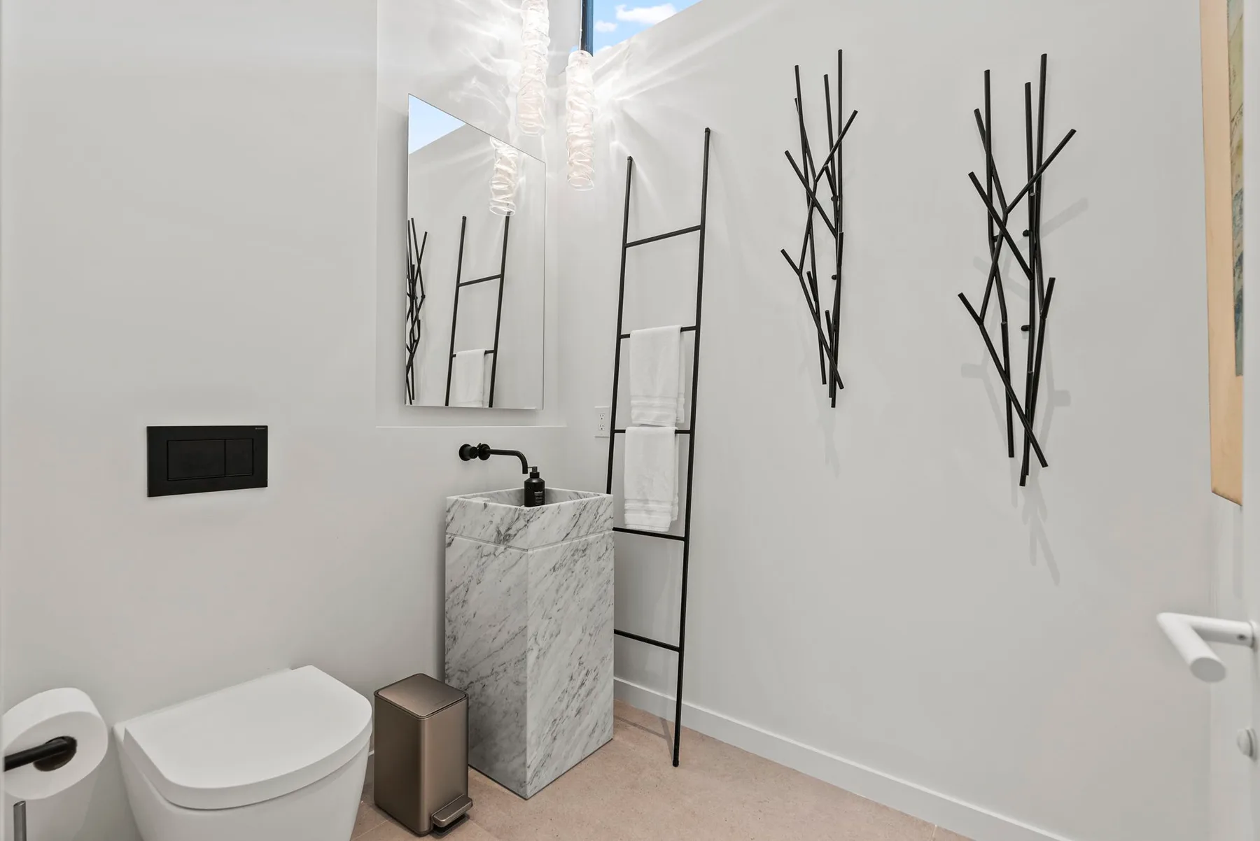 A modern bathroom with a toilet, sink, and black wall-mounted towel racks.