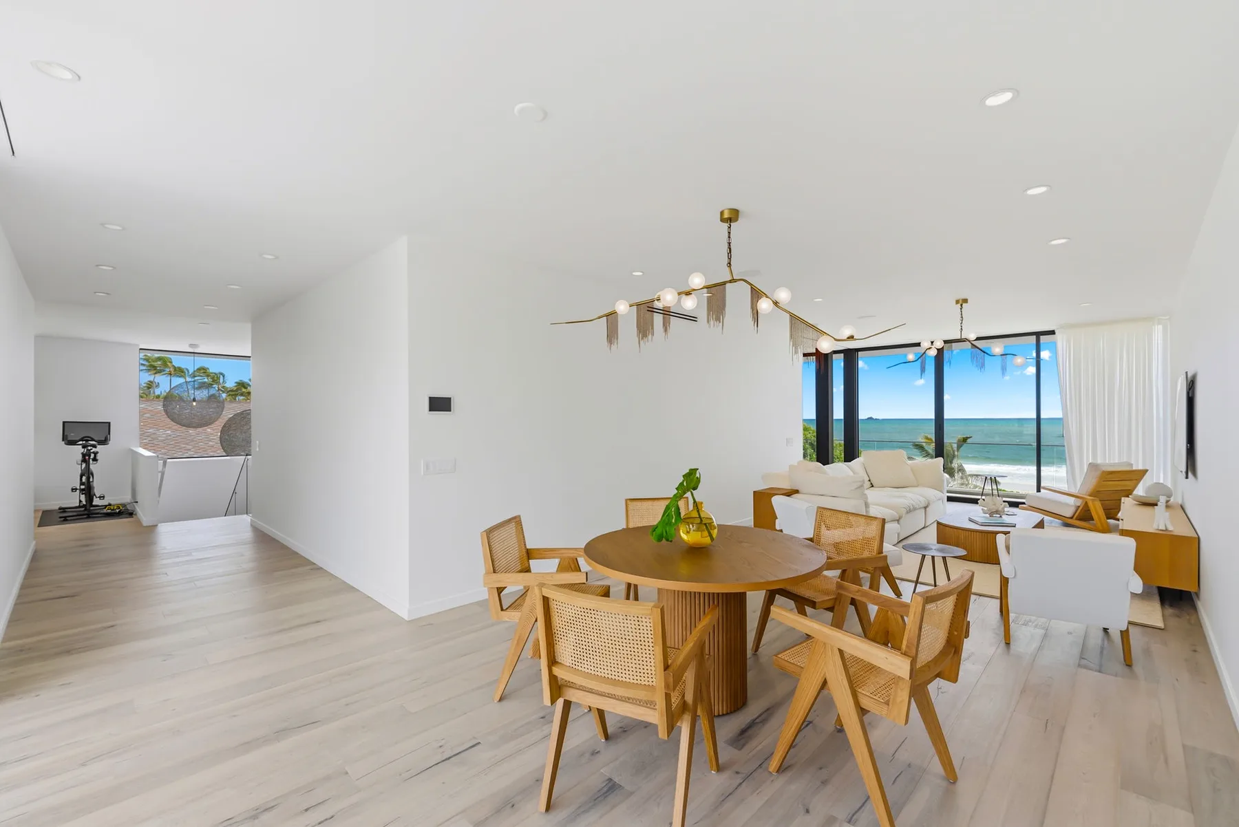 A bright open-plan living and dining area with large windows overlooking the ocean.