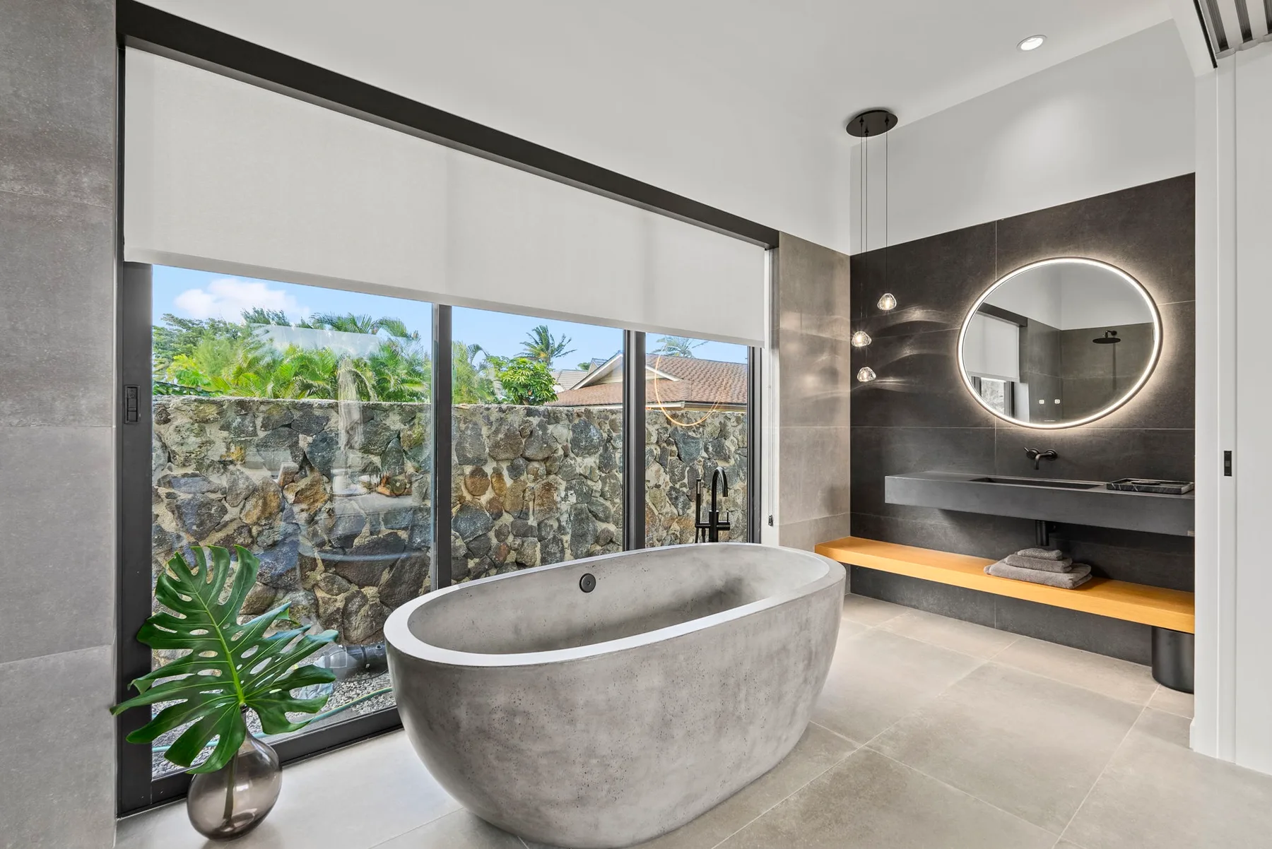 A modern bathroom with a freestanding bathtub beside a large window.