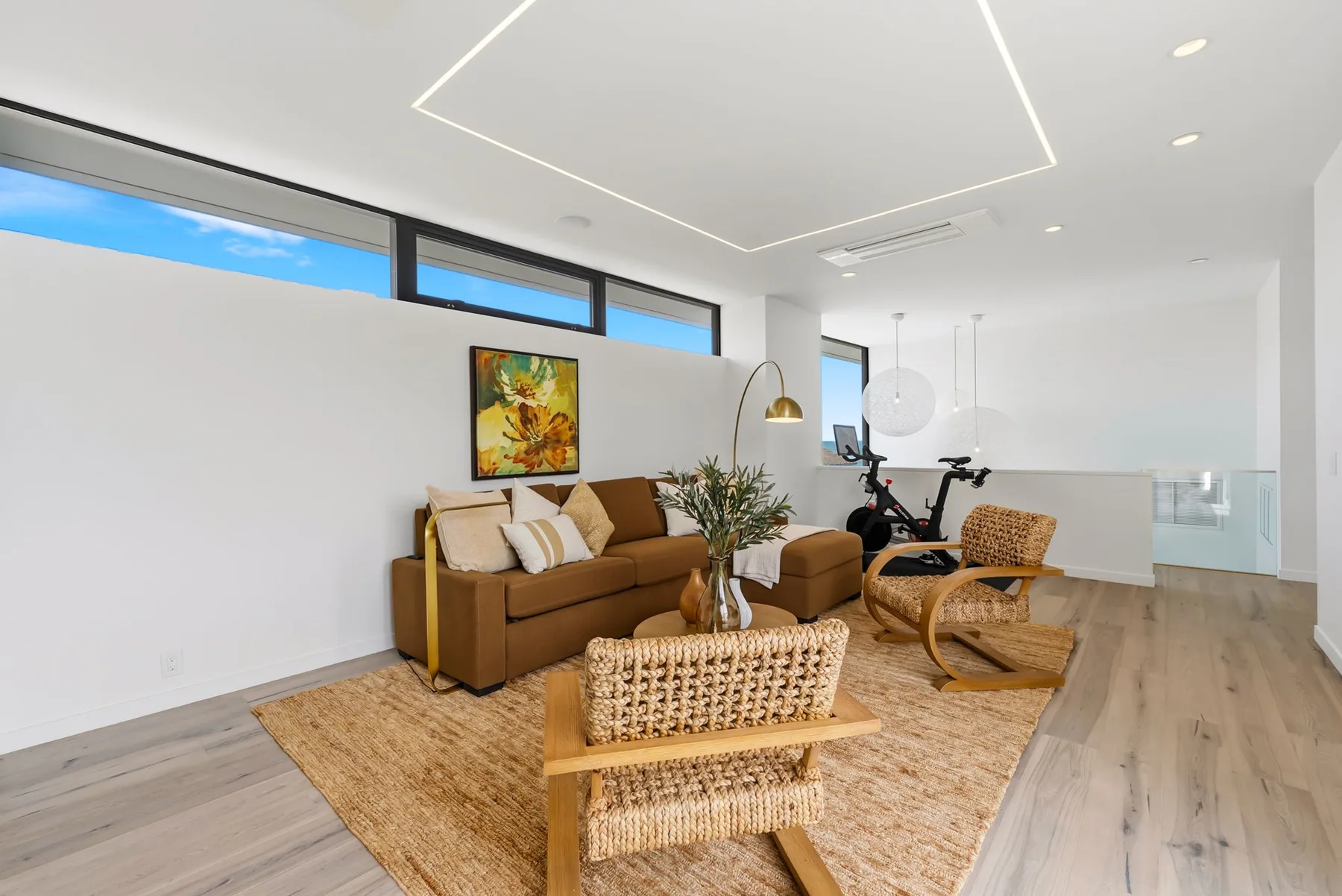 A bright living room with seating arranged around a woven coffee table.