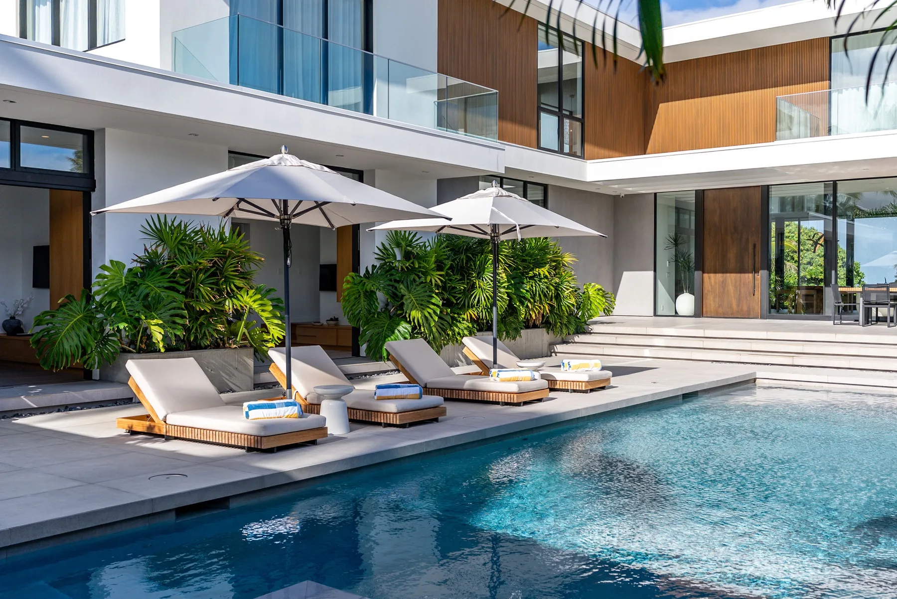 A swimming pool beside a modern building, with shaded seating along the water.