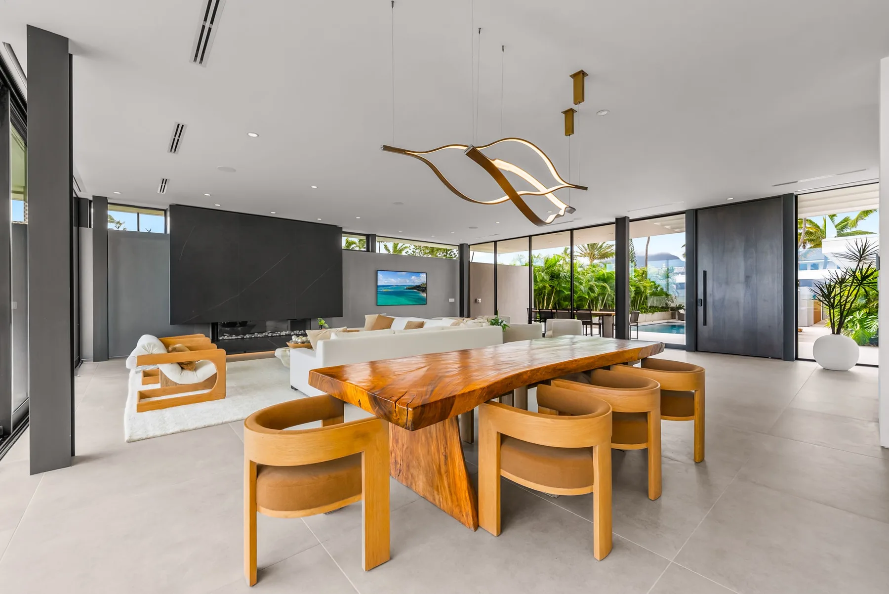 A bright open-plan living and dining room with a wooden dining table and large windows.