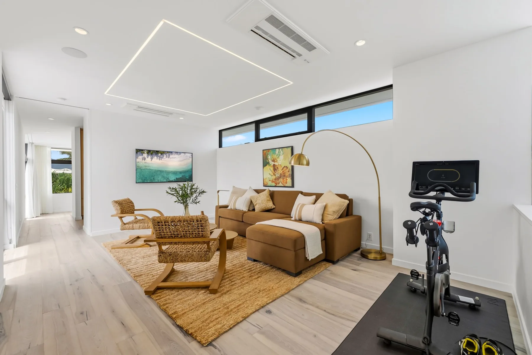 A bright living room with seating, a rug, and an exercise bike.