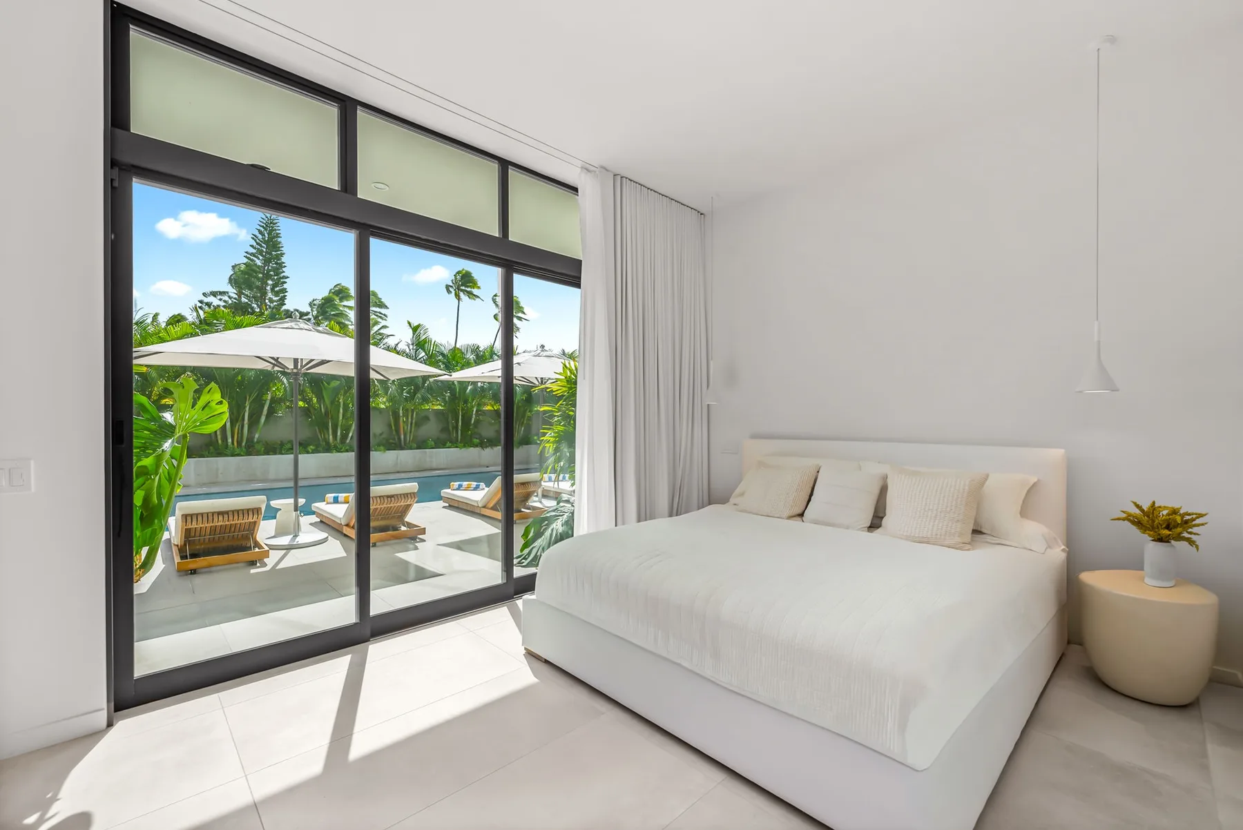 A bright bedroom with a bed beside large sliding glass doors overlooking a patio.