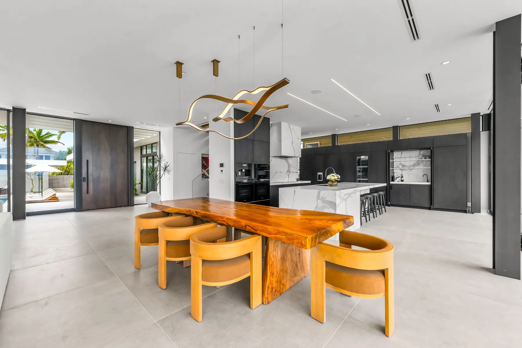 A modern kitchen and dining area with a long wooden table and seating.