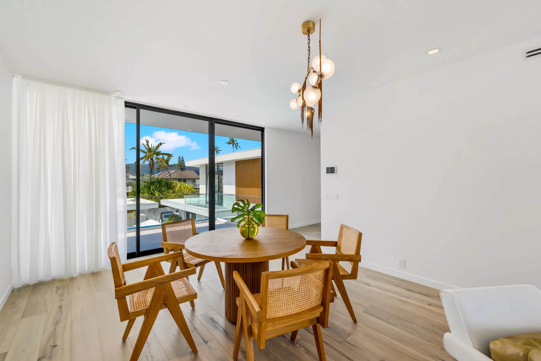 A bright dining area has a round wooden table beside large windows.