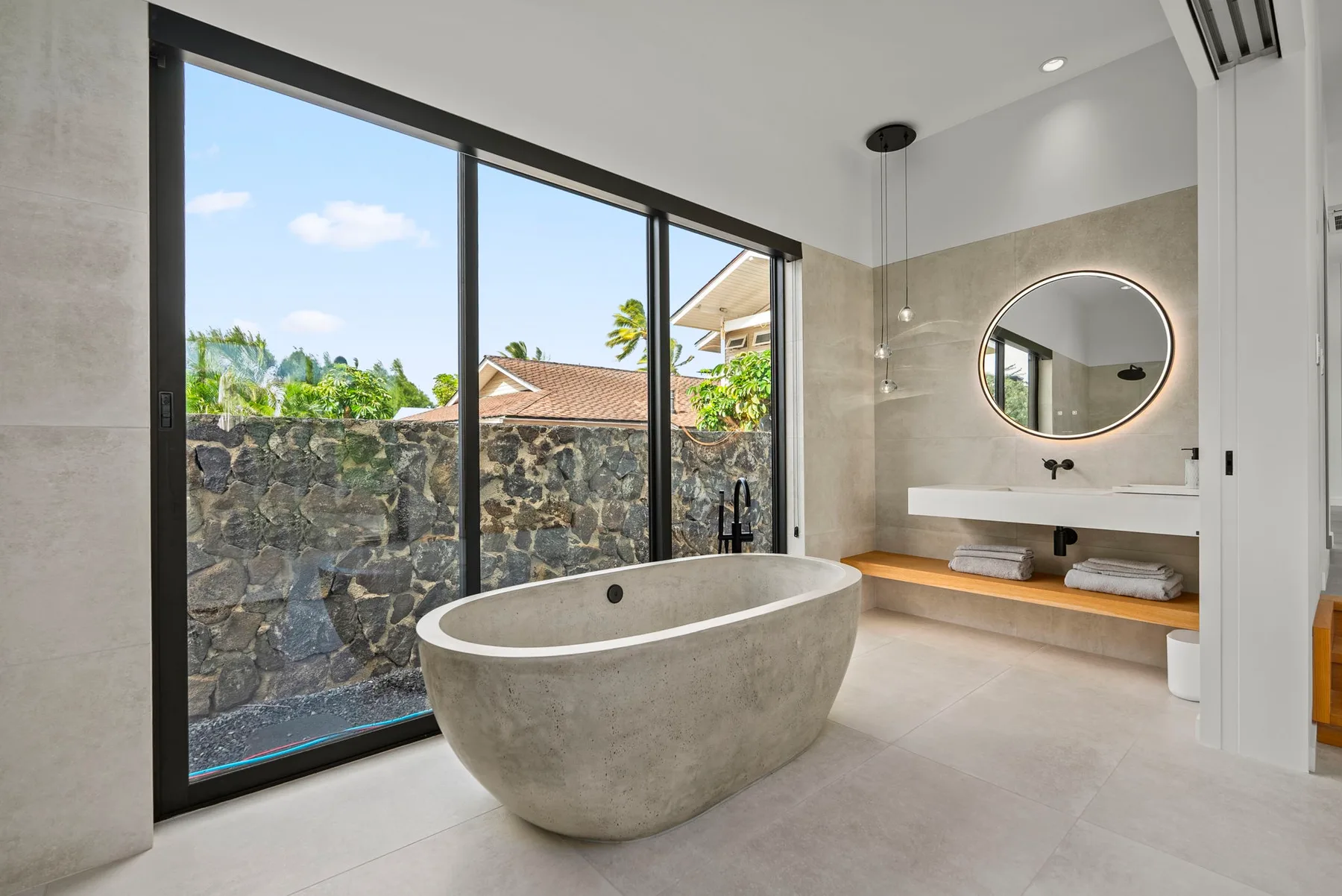 A bright bathroom has a freestanding tub beside large glass doors.