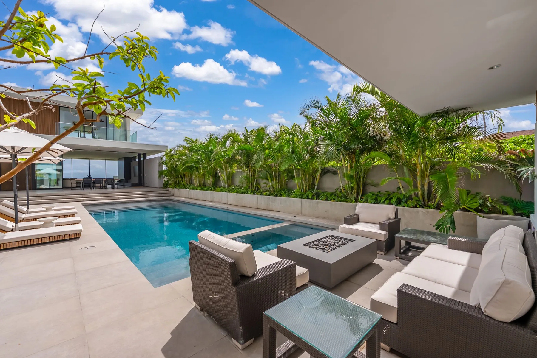 A modern outdoor patio with a swimming pool and cushioned seating.